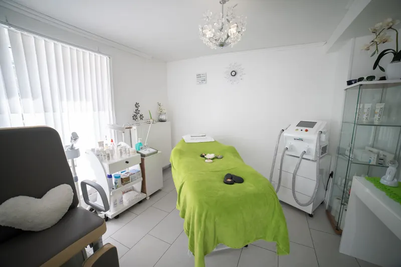 Cabina estetica luminosa con lettino e mobili bianchi.