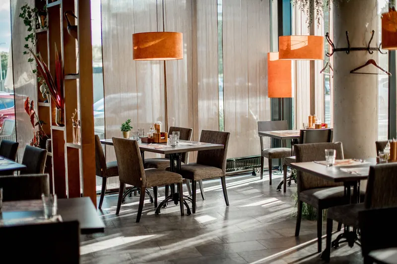 Sala di un ristorante con tavoli apparecchiati e lampade arancioni.